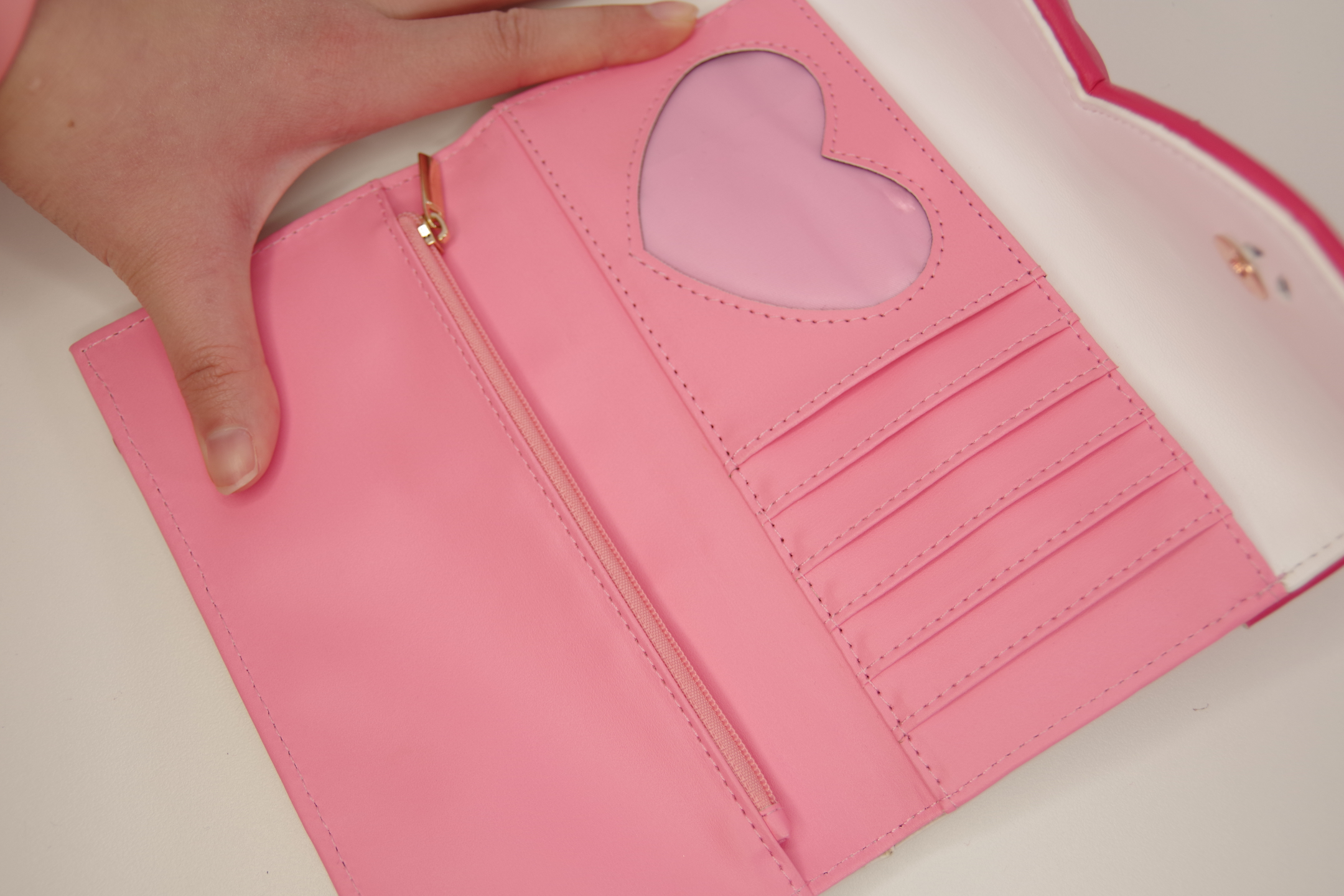 Interior view of a pink magical girl inspired wallet featuring multiple card slots, a zippered coin pocket, and a heart-shaped ID window.