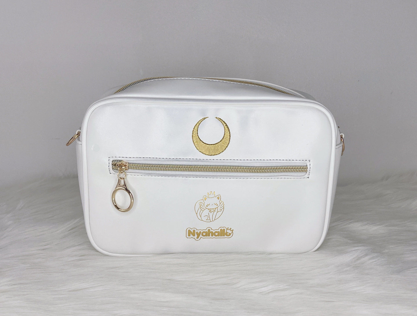 Back view of a white and gold celestial crossbody bag featuring a crescent moon emblem, zip pocket, and moon princess inspired design.